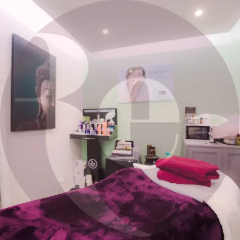 The treatment room, with a massage couch, plum blanket and skincare products